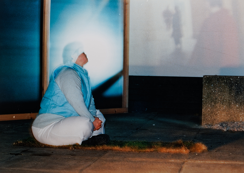 Photo of Laura outside Tate Modern sitting on some turf in the performance In Full Colour