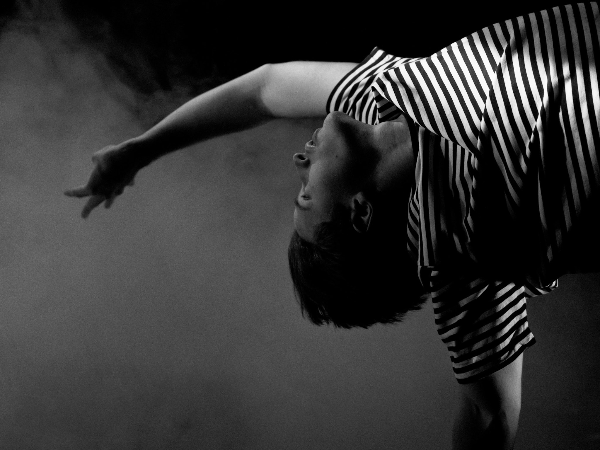 Black and white photo of Paul dancing in a striped top and arm outstretched behind him